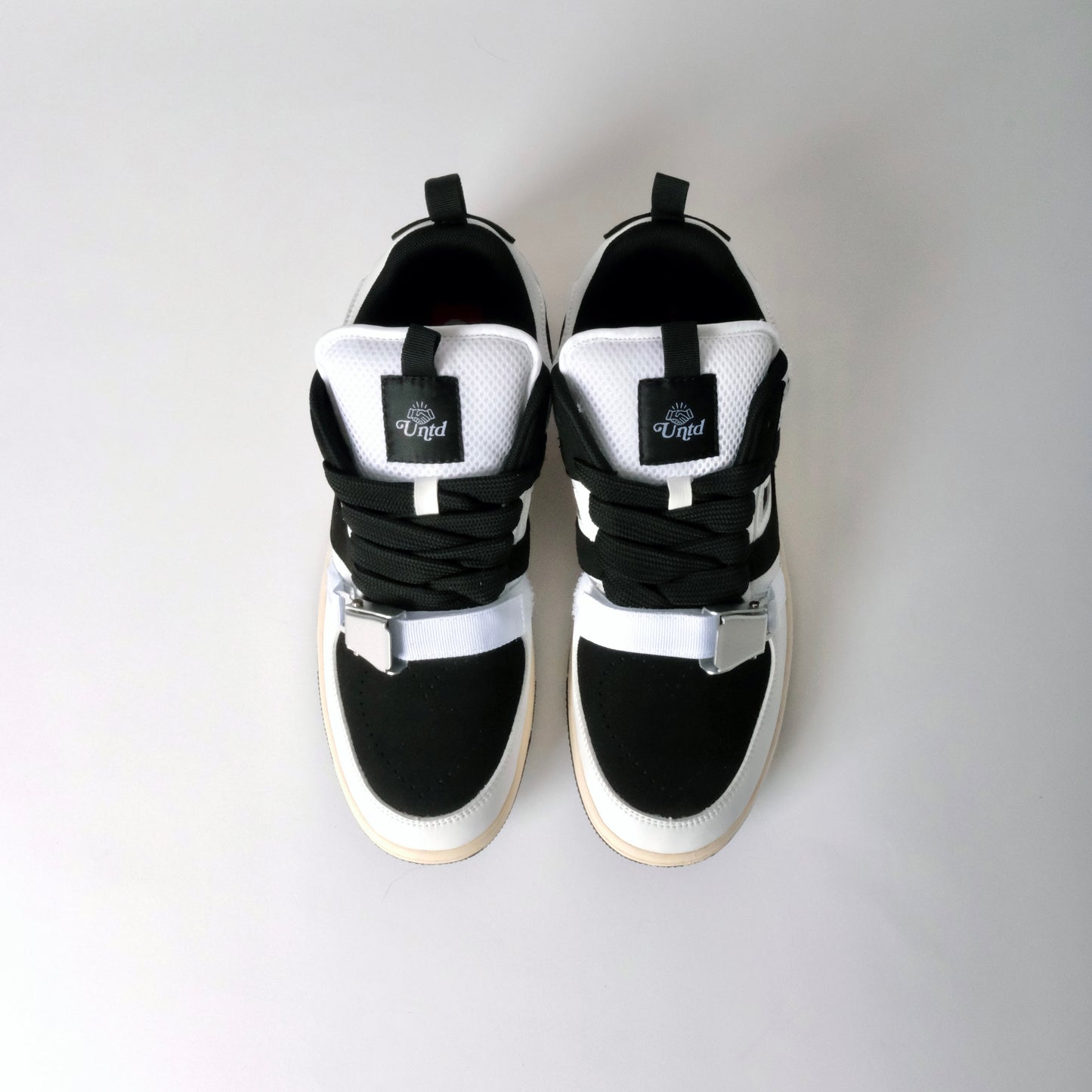 UNTD Amity Low Panda shoe with black toe box, white side panels, and thick black laces